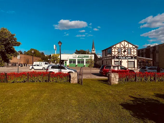 The shop seen from the park across the street, next to the Tudor-style pub, under a blue sky.